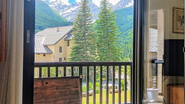 A balcony with a view of mountains and trees. - Cosy apartment with balcony (Le Monêtier-les-Bains)