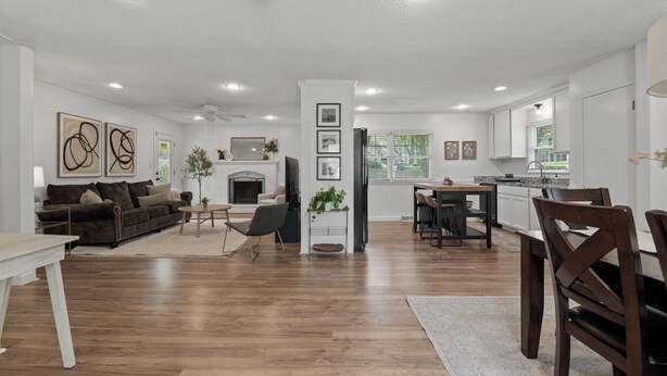 A spacious living area with a fireplace, a dining area, and a kitchen with white cabinets. - Spacious 4-bedroom Home in South Kansas City (Kansas City)