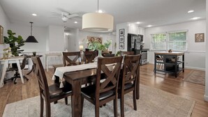 A modern kitchen with white cabinets, a dining area with wooden chairs, a ceiling fan, and recessed lighting. - Spacious 4-bedroom Home in South Kansas City (Kansas City)