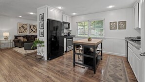 A modern kitchen with white cabinetry, a black refrigerator, and a dining area with a wooden table and chairs. - Spacious 4-bedroom Home in South Kansas City (Kansas City)