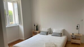 Un dormitorio con una cama grande, dos mesitas de noche, una ventana y una lámpara de noche.