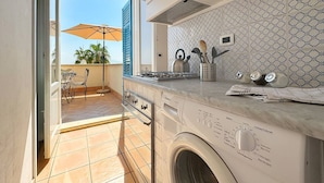 Una cucina compatta con lavatrice, schienale piastrellato e vista sull'esterno.