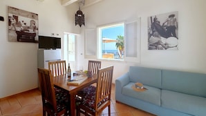 Zona pranzo con tavolo e sedie in legno, un divano blu e opere d'arte alle pareti.