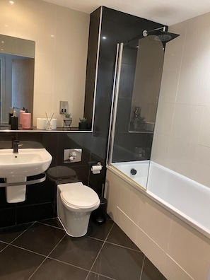 Une salle de bain moderne avec une douche à parois de verre, un lavabo blanc et des toilettes.