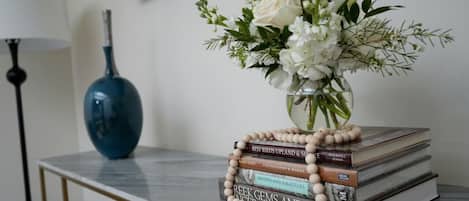 A marble table with a vase of white flowers, a stack of books, and a blue vase.