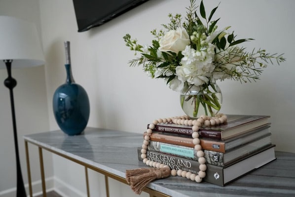 A marble table with a vase of white flowers, a stack of books, and a blue vase.
