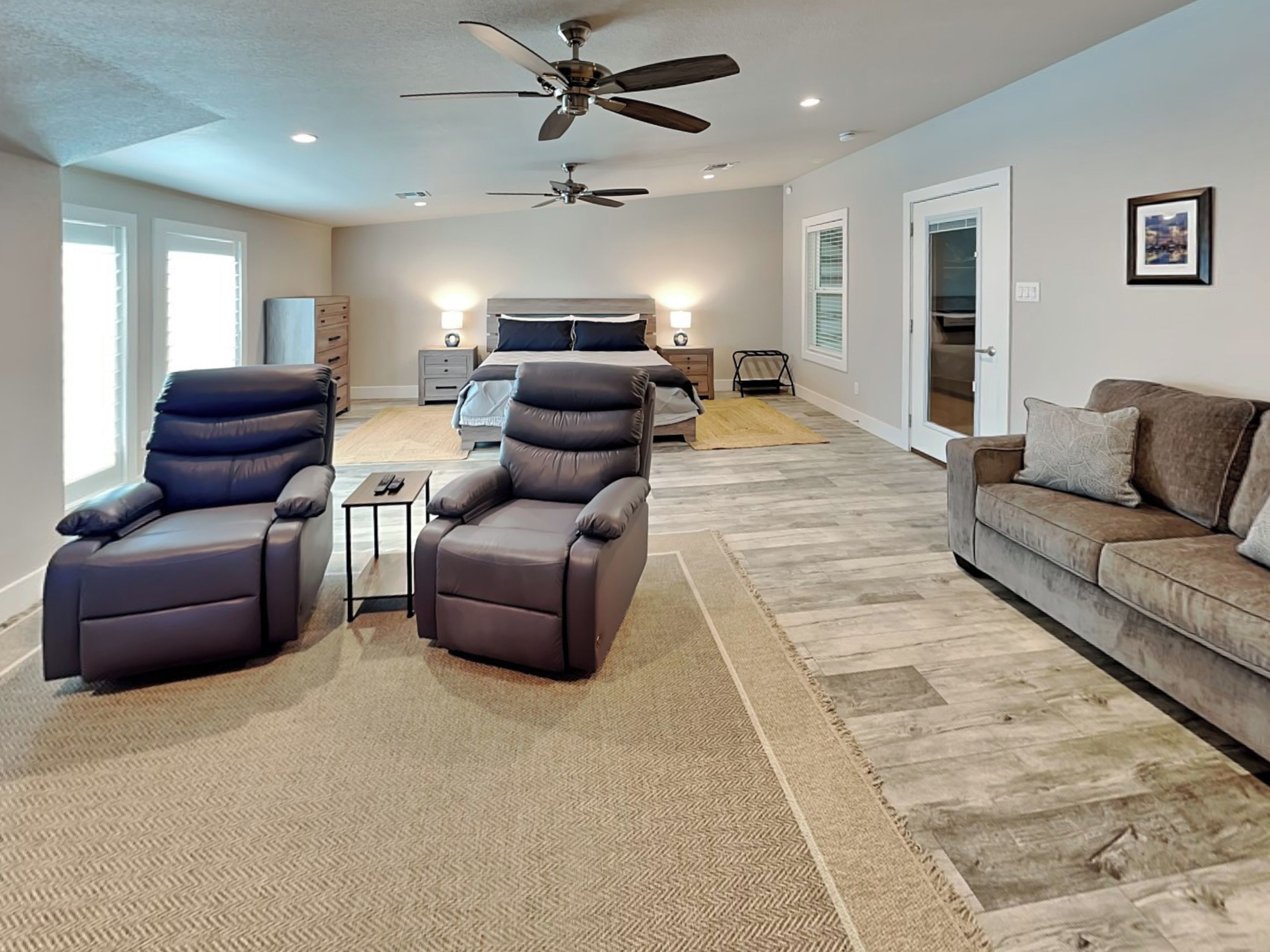 A spacious living room with a large sofa, two recliner chairs, a coffee table, and a ceiling fan.