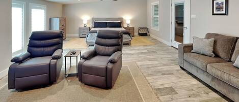 A spacious living room with a large sofa, two recliner chairs, a coffee table, and a ceiling fan.