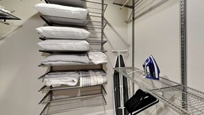 A storage closet with shelves holding pillows, folded blankets, and a vacuum cleaner. - Heron's Roost by Miss Kitty’s (Rockport)