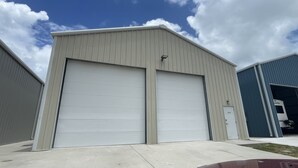 A large industrial building with two large garage doors, a small door labeled "2012", and a truck parked inside. - Heron's Roost by Miss Kitty’s (Rockport)