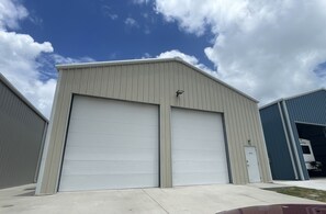 A large industrial building with two large garage doors, a small door labeled "2012", and a truck parked inside.