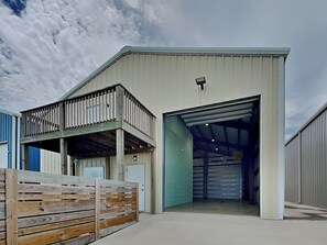 A warehouse-style building with a flat roof, a balcony, and a large garage door. - Heron's Roost by Miss Kitty’s (Rockport)