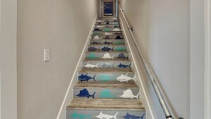 A staircase with wooden steps and shark designs. - Heron's Roost by Miss Kitty’s (Rockport)
