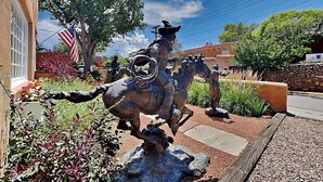 A bronze equestrian statue in a landscaped area with a building in the background. - Casa en Canyon by Kokopelli Property Management (Santa Fe)