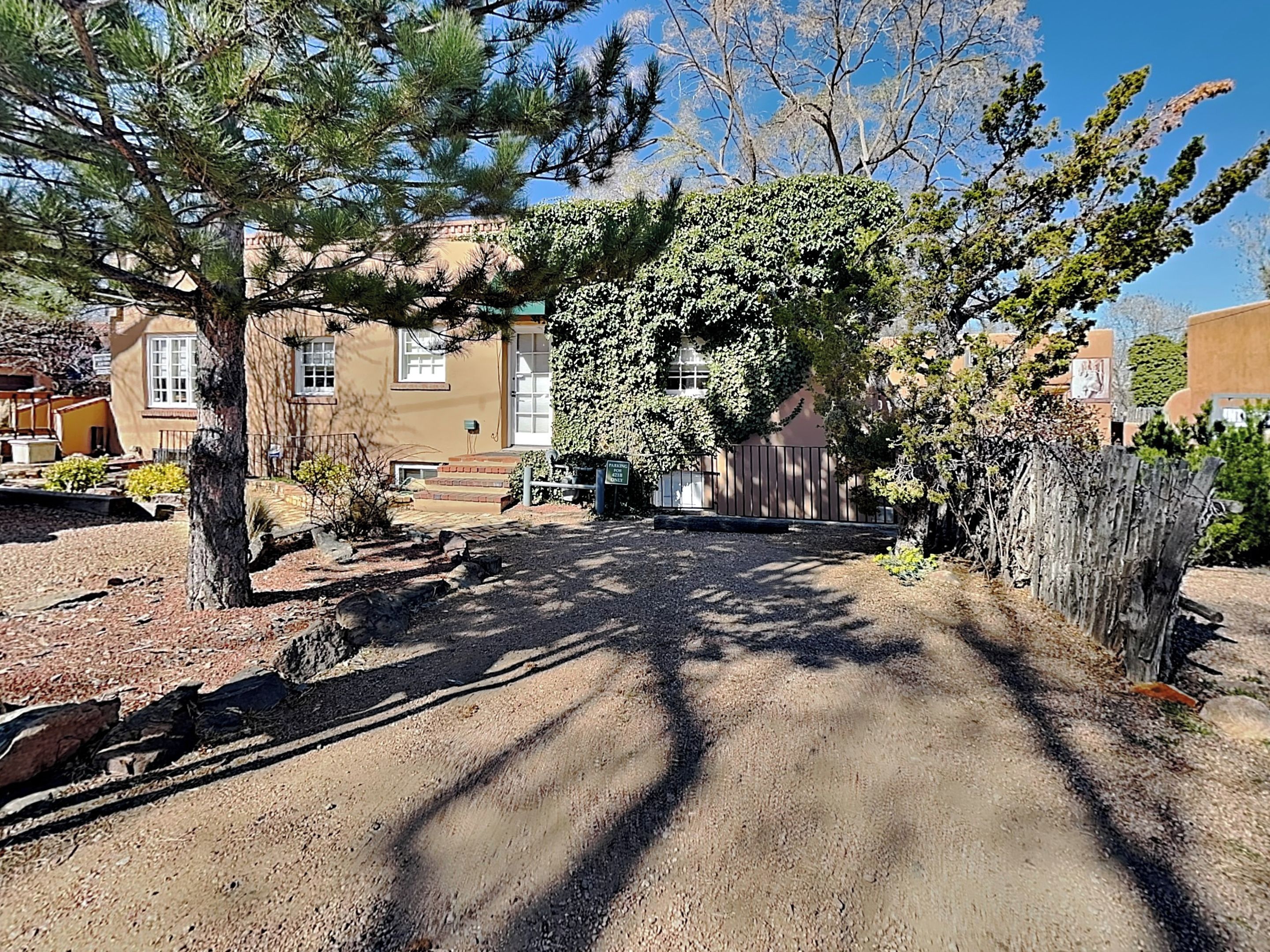 A residential area with a paved driveway leading to a house with a front yard, a tree, and a fence.