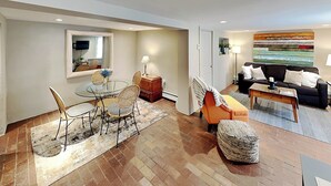 A modern living room with a glass dining table, wicker chairs, a sofa, and a coffee table. - Casa en Canyon by Kokopelli Property Management (Santa Fe)