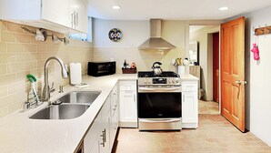 A modern kitchen with white cabinetry, stainless steel appliances, and a tiled backsplash. - Casa en Canyon by Kokopelli Property Management (Santa Fe)