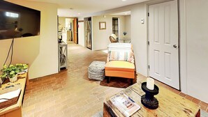 A hotel room with a bed, a television, a small table with a magazine, a plant, and a door leading to the hallway. - Casa en Canyon by Kokopelli Property Management (Santa Fe)