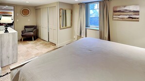 A bedroom with a bed, a chair, a desk, a window with curtains, and a painting on the wall. - Casa en Canyon by Kokopelli Property Management (Santa Fe)