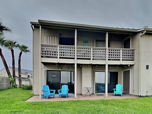 Un bâtiment à deux étages doté d’un balcon, de grandes fenêtres et d’un espace extérieur aménagé avec des chaises.