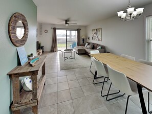 Un vaste espace de vie comprenant une table à manger, des chaises blanches, un canapé et une table basse.