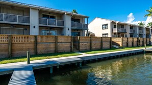 Un hôtel situé au bord de l’eau, doté de nombreux balcons, d’une terrasse en bois et d’une piscine.