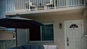 Un bâtiment à deux étages doté d’un balcon, d’un espace extérieur aménagé pour s’asseoir et d’une porte.