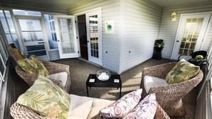 A covered patio area with wicker furniture and a small table. - Margarita House in The Villages close to both Lake Sumpter and Spanish Springs! (The Villages)