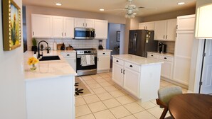 A modern kitchen with white cabinets, stainless steel appliances, and a central island. - Margarita House in The Villages close to both Lake Sumpter and Spanish Springs! (The Villages)