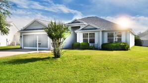 A two-story house with a garage, a well-maintained lawn, and a small tree in the front yard. - Margarita House in The Villages close to both Lake Sumpter and Spanish Springs! (The Villages)