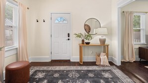 A hallway with a white door, a console table with a mirror, a vase, and a bench. - Charming 1-bedroom house with WiFi, AC in peaceful Cleveland 3215 (Cleveland)