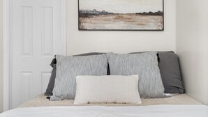 A bed with striped and solid pillows, a plain wall, and a framed picture above it. - Charming 1-bedroom house with WiFi, AC in peaceful Cleveland 3215 (Cleveland)