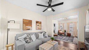 A modern living room with a grey sofa, a standing lamp, and a ceiling fan. - Charming 1-bedroom house with WiFi, AC in peaceful Cleveland 3215 (Cleveland)