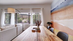 A dining area with a wooden table, white upholstered seating, and a view of the outdoors through large windows. - Fully Remodeled Mountain Condo, Silverthorne, A1 Brian (Silverthorne)