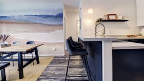A modern kitchen with a bar area, a dining table with chairs, and a large abstract mural on the wall. - Fully Remodeled Mountain Condo, Silverthorne, A1 Brian (Silverthorne)