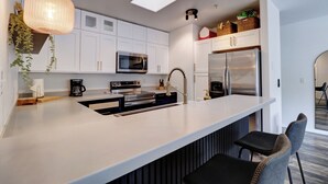 A modern kitchen with white cabinets, stainless steel appliances, a large island with seating, and pendant lighting. - Fully Remodeled Mountain Condo, Silverthorne, A1 Brian (Silverthorne)
