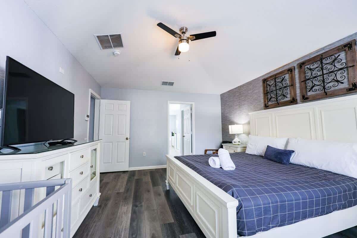 Une chambre à coucher avec un lit, une télévision, un ventilateur de plafond et une porte.