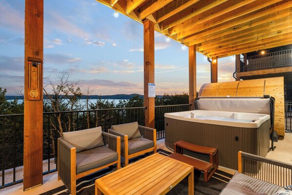 Una terraza al aire libre con muebles de madera, un jacuzzi y vistas al paisaje.
