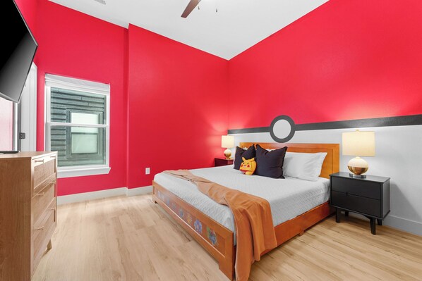 Un dormitorio con pared roja, una cama de madera, una mesita de noche con lámpara y una ventana con persianas.