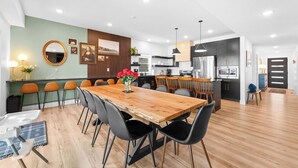 Una cocina moderna con armarios oscuros, un refrigerador de acero inoxidable y una mesa de comedor de madera con sillas negras.