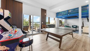 Una habitación moderna con mesa de ping pong, mesa de fútbol y un amplio ventanal con vistas al exterior.