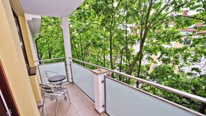 A balcony with a table and chairs, surrounded by trees and buildings. - Duet by Grand Apartments (Sopot)