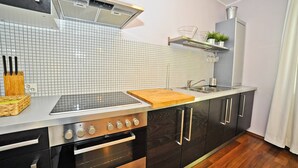 A modern kitchen with a stainless steel stove, black cabinets, and a tiled backsplash. - Duet by Grand Apartments (Sopot)