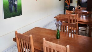 A dining area with wooden tables and chairs, a chandelier, and wall decorations including a painting of an elephant and a red leaf design. - Pouso do Carteiro (Tiradentes)