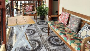 A wooden balcony with a patterned floor, a wooden bench, and a table. - Pouso do Carteiro (Tiradentes)
