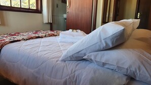 A neatly made bed with white bedding and a floral-patterned throw blanket. - Pouso do Carteiro (Tiradentes)