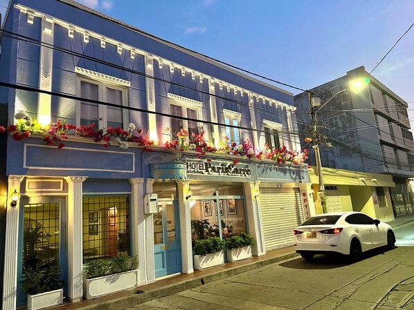 A hotel facade with a blue exterior, a sign reading "HOTEL ParisCarne," and a white car parked in front. - HOTEL PARIS CARRE (Valledupar)
