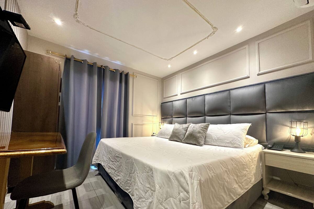 A modern hotel room with a large bed, a desk, and a chair.
