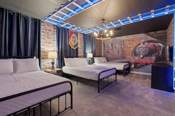 Ein Hotelzimmer mit zwei Betten, einer Backsteinwand, einem Wandgemälde eines Zuges und einer Decke mit blauer Beleuchtung.