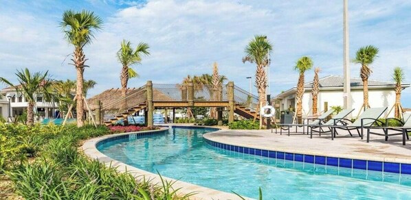 A swimming pool with palm trees, lounge chairs, and a covered area.